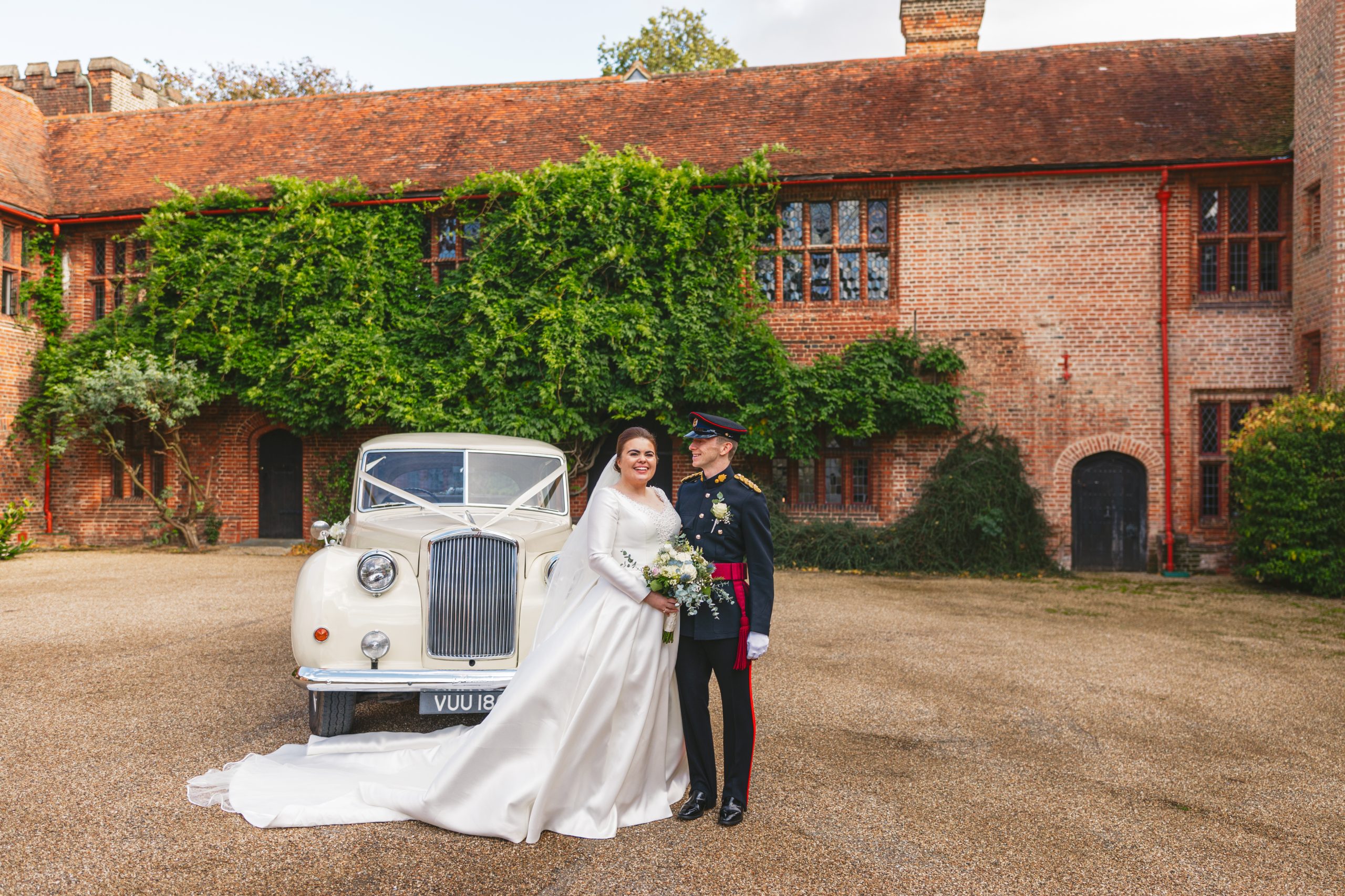 Bride and groom portrait outside Ingatestone Hall with vintage wedding car in Essex