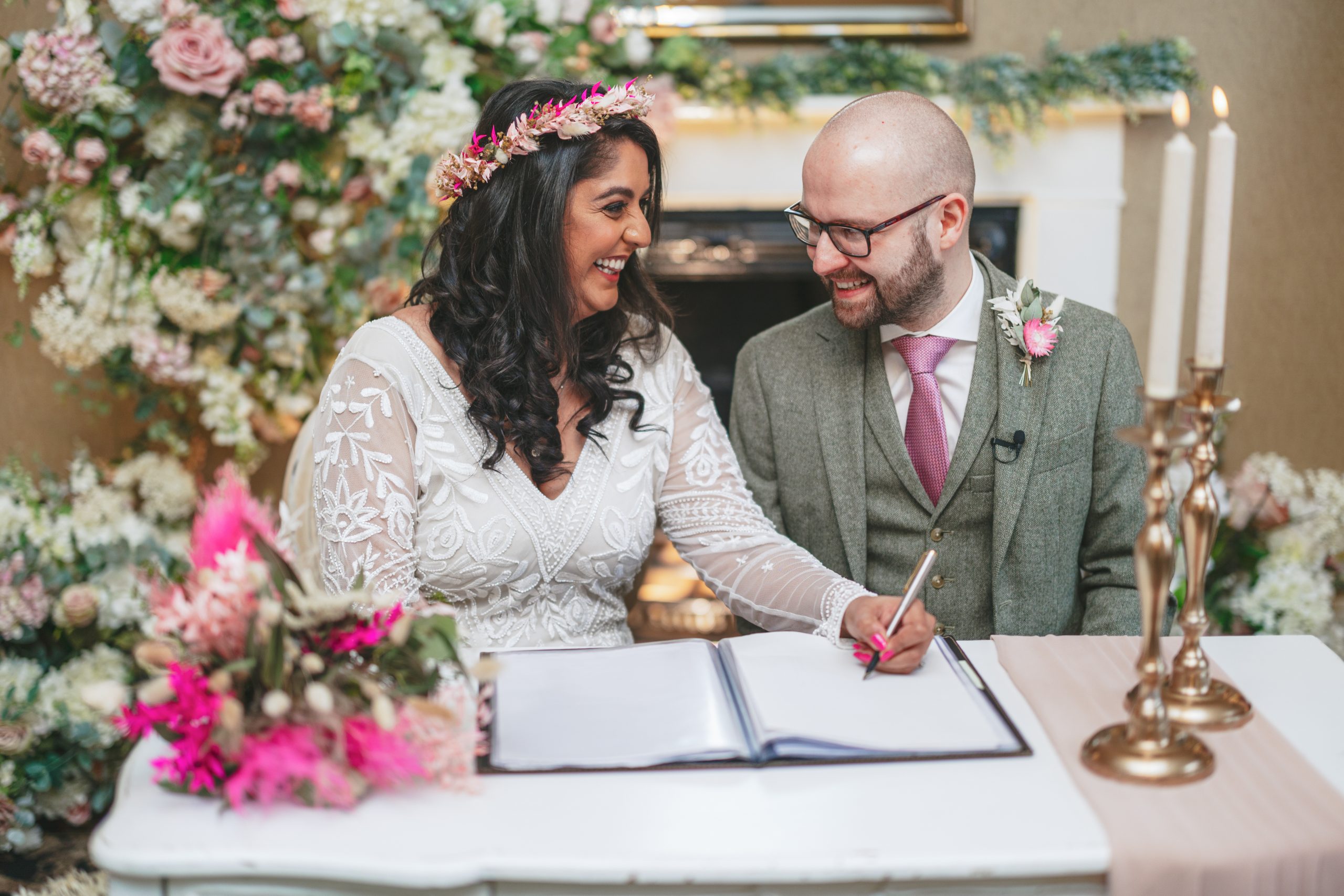Bride and groom smiling while signing marriage register at City Rooms Leicester